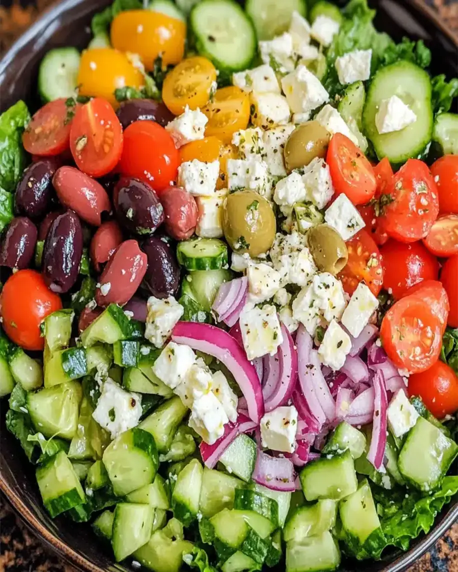 A vibrant Greek salad with fresh vegetables, olives, and feta cheese, drizzled with dressing.