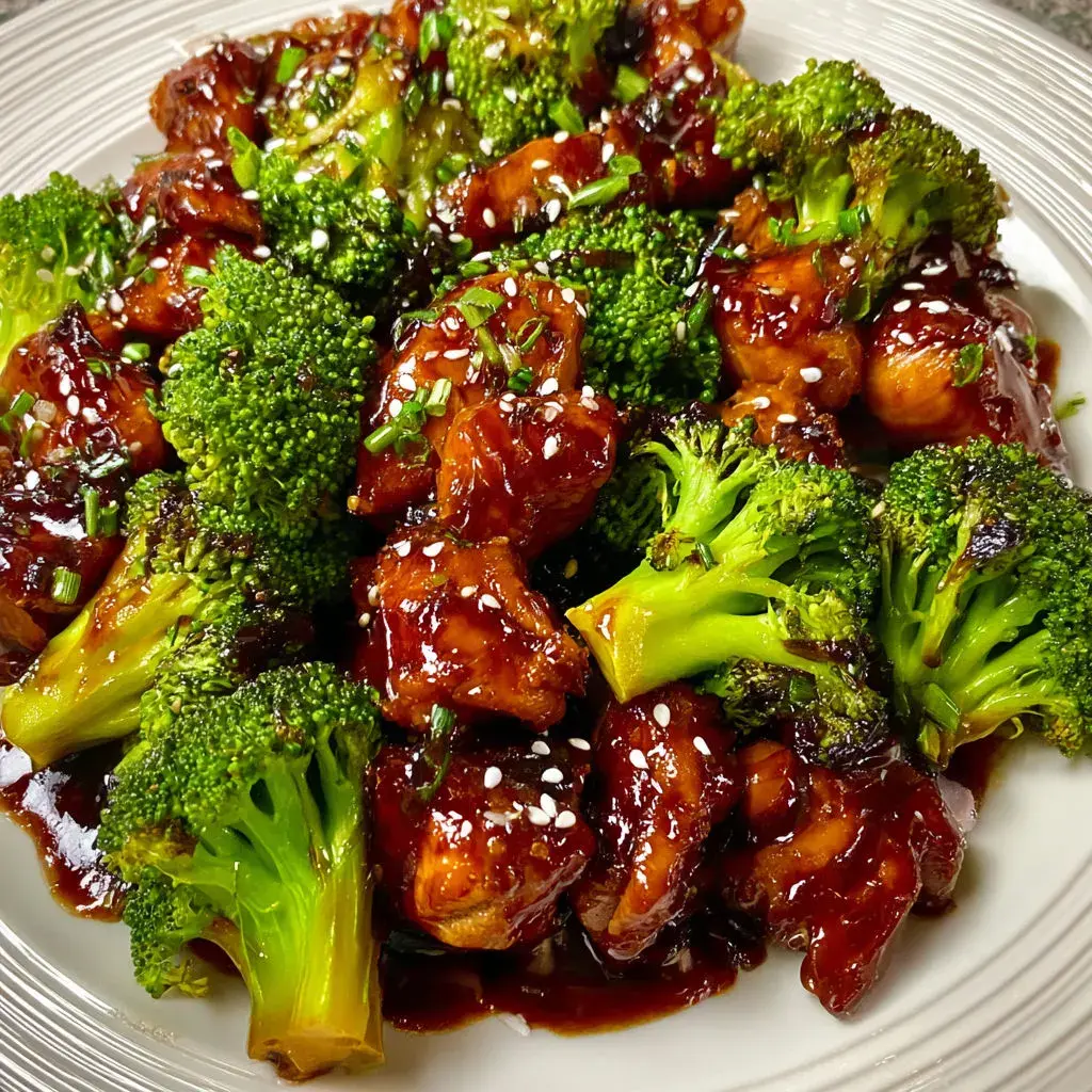 Plated bourbon chicken with broccoli, ready to serve with sauce glistening over tender chicken and broccoli.