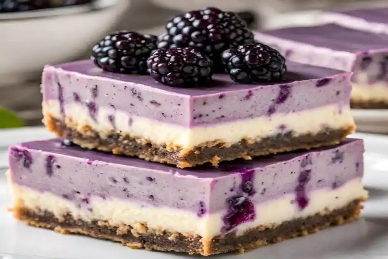 Delicious looking blackberry cheesecake bars arranged on a platter.